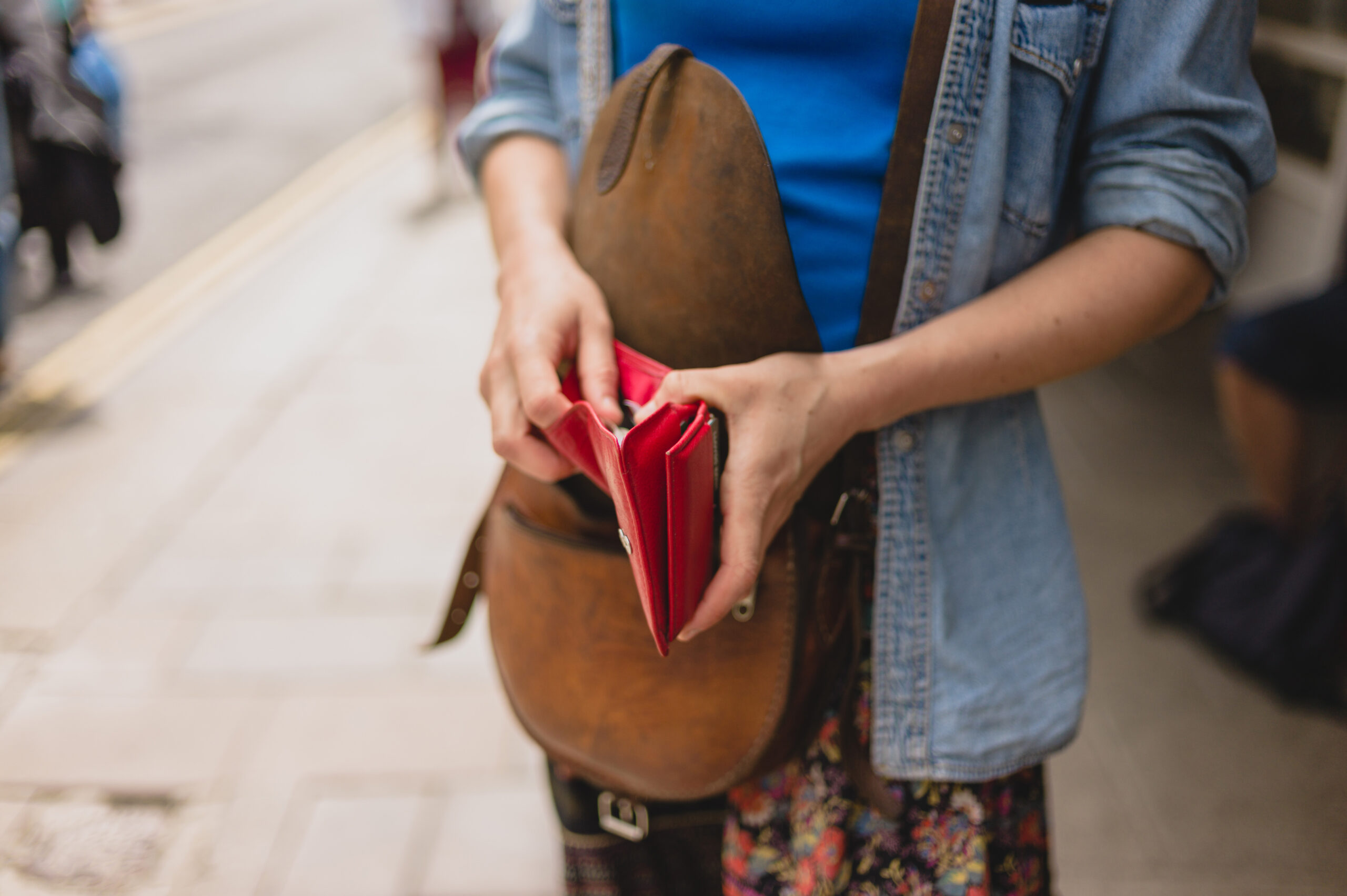 woman pulling a red wallet out of a brown purse